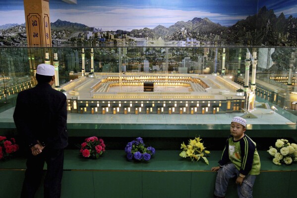 FILE - A Chinese Hui Muslim looks at a scale model of Mecca set up at a mosque in the town of Yichuan during Ramadan in Ningxia province, China, Saturday, Oct. 21, 2006. The Chinese government has expanded its campaign of shuttering mosques to provinces other than Xinjiang, where Beijing has for years been blamed of persecuting Muslim minorities, according to a report released Wednesday by Human Rights Watch. (AP Photo/Elizabeth Dalziel, File)