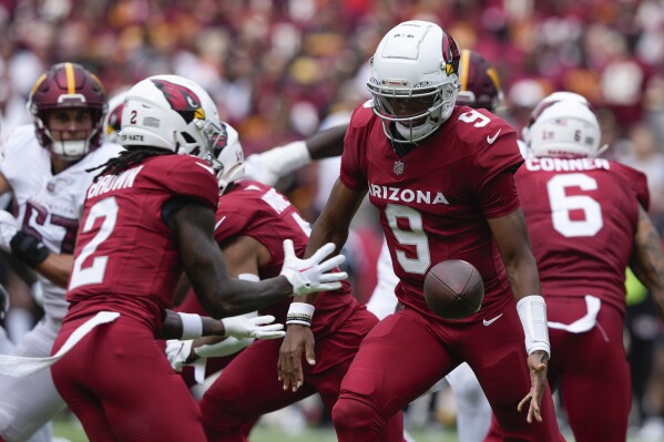 Arizona Cardinals quarterback Joshua Dobbs (9) tosses the ball to wide receiver Marquise Brown (2) during the first half of an NFL football game against the Washington Commanders, Sunday, Sept. 10, 2023, in Landover, Md. (AP Photo/Susan Walsh)