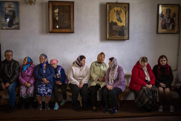 Women wait for the start of a religious service to commemorate the fallen during the Russian occupation in Zdvyzhivka, on the outskirts of Kyiv, on Saturday, April 30, 2022. (AP Photo/Emilio Morenatti)