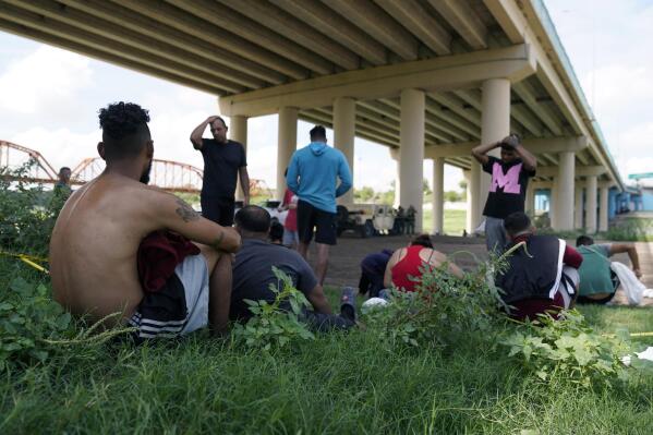 FILE - Migrants wait to be processed by the Border Patrol after illegally crossing the Rio Grande river from Mexico into the U.S. at Eagle Pass, Texas, Friday, Aug. 26, 2022. The number of Venezuelans, Cubans and Nicaraguans taken into custody at the U.S. border with Mexico soared in August as migrants from Mexico and traditional sending countries were stopped less frequently, authorities said Monday, Sept. 19. (AP Photo/Eric Gay, File)