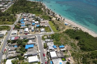 
              FILE - This June 18, 2018 file photo shows an aerial photo of the Viequez neighborhood, east of San Juan, Puerto Rico, where people were still living in damaged homes, protected by blue plastic tarps, nine months since Hurricane Maria devastated the island. Puerto Rico's governor said on Tuesday, Sept. 11, 2018 that his administration has adopted new measures to better prepare for a disaster like Maria while he warned of limitations given the U.S. territory's economic crisis. (AP Photo/Dennis M. Rivera, File)
            