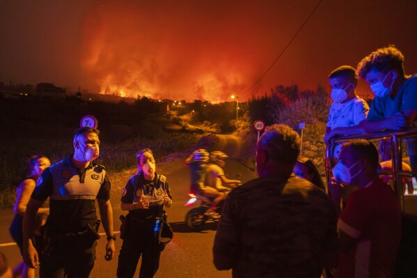 Residents try to reach their houses in Benijos village as police block the area as a wildfire advances in La Orotava in Tenerife, Canary Islands, Spain on Aug. 19, 2023. (AP Photo/Arturo Rodriguez)