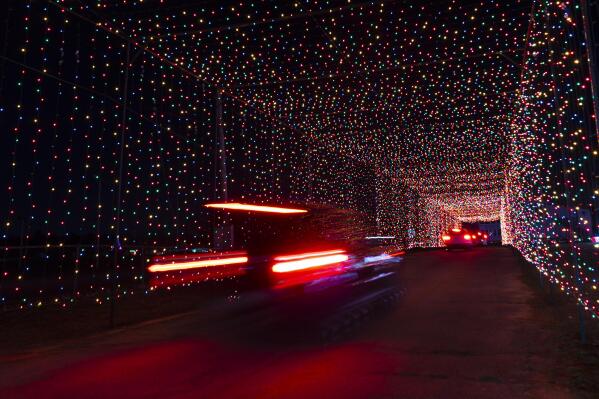 Passenger vehicles move through a tunnel of holiday lights at a display set up at the Cumberland Fair Grounds, Tuesday, Dec. 14, 2021, in Cumberland, Maine. The holiday season has become more sparkly during the COVID-19 pandemic, with people and businesses pouring money into light shows to spread cheer. (AP Photo/Robert F. Bukaty)
