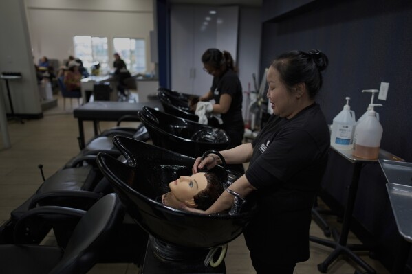 Hoang Le, a Vietnamese student at Advance Beauty College who moved to the U.S. in 2022, practices hair washing on a mannequin in the Little Saigon neighborhood of Garden Grove, Calif., Wednesday, April 23, 2025. (AP Photo/Jae C. Hong)