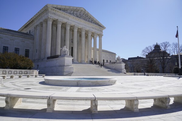 FILE - People stand on the steps of the U.S. Supreme Court, Feb.11, 2022, in Washington. The Supreme Court is taking up challenges by commercial fishermen to a fee requirement that could achieve a long-sought goal of business and conservative interests, limiting a wide range of government regulations. Billions of dollars are potentially at stake. (AP Photo/Mariam Zuhaib, File)