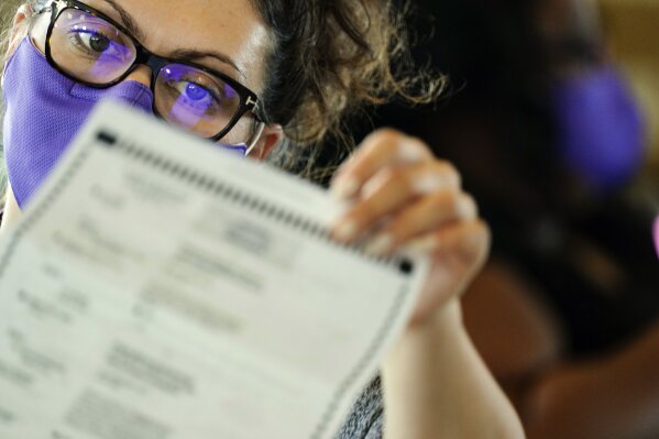 FILE - In this Thursday, Nov. 5, 2020 file photo, an election worker examines ballots as vote counting in the general election continues at State Farm Arena in Atlanta. On Friday, Nov. 6, 2020, The Associated Press reported on stories circulating online incorrectly asserting that election officials in DeKalb County rejected 40,000 absentee ballots. As of Nov. 4, county election officials had only identified about 200 problematic mailed ballots. Officials were reaching out to voters in an effort to resolve issues before the Nov. 6 deadline to do so. (AP Photo/Brynn Anderson)