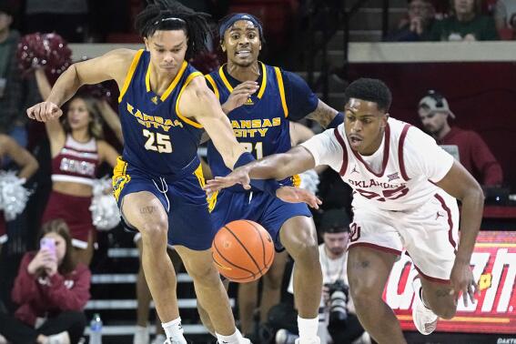 Kansas City guard Tyler Andrews (25) and Oklahoma guard Grant Sherfield, right, reach for the ball in front of Kansas City guard RayQuawndis Mitchell, center, in the first half of an NCAA college basketball game, Tuesday, Dec. 6, 2022, in Norman, Okla. (AP Photo/Sue Ogrocki)
