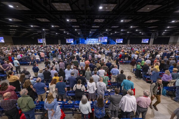 Messengers stand for worship during a Southern Baptist Convention annual meeting Tuesday, June 11, 2024, in Indianapolis. (AP Photo/Doug McSchooler, File)