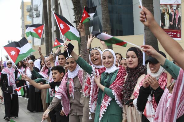 Jordanians wave the national flags in anticipation of the royal motorcade in Amman, Jordan on Thursday, June 1, 2023, just ahead of Crown Prince Hassan and saudiSaudi architect Rajwa Alseif's wedding. (AP Photo/Raad Adayleh)