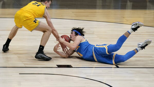 UCLA guard Jaime Jaquez Jr. battles for a loose ball with Michigan guard Franz Wagner (21) during the first half of an Elite 8 game in the NCAA men's college basketball tournament at Lucas Oil Stadium, Tuesday, March 30, 2021, in Indianapolis. (AP Photo/Michael Conroy)