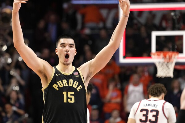 Purdue's Zach Edey (15) celebrates the team's 77-71 win over Illinois, while Illinois' Coleman Hawkins (33) walks off the court after an NCAA college basketball game Tuesday, March 5, 2024, in Champaign, Ill. (AP Photo/Charles Rex Arbogast)