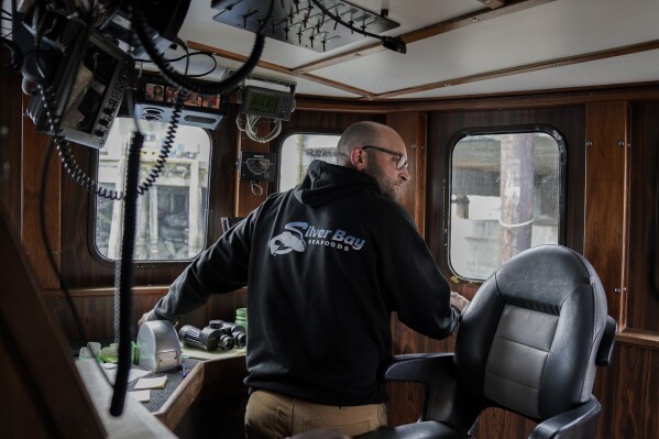 Kevin Abena, who runs a fishing business with his father, looks back as he steers his boat away from a processor's dock, Sunday, June 25, 2023, in Kodiak, Alaska. (AP Photo/Joshua A. Bickel)