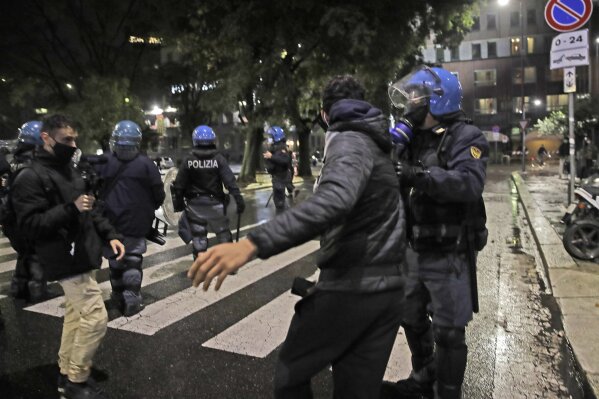 A police officer confronts a man during a protest against the government restriction measures to curb the spread of COVID-19, in Milan Italy, Monday, Oct. 26, 2020. Italy's leader has imposed at least a month of new restrictions to fight rising coronavirus infections, shutting down gyms, pools and movie theaters and putting an early curfew on cafes and restaurants. (AP Photo/Luca Bruno)