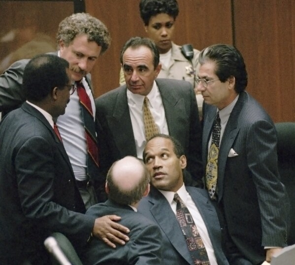 FILE- Defendant O.J. Simpson is surrounded by his defense attorneys, from left, Johnnie L. Cochran Jr., Peter Neufeld, Robert Shapiro, Robert Kardashian, and Robert Blasier, seated at left, at the close of defense arguments in his murder trial, Thursday, Sept. 28, 1995, in Los Angeles. Simpson, the decorated football superstar and Hollywood actor who was acquitted of charges he killed his former wife and her friend but later found liable in a separate civil trial, has died. He was 76. (Sam Mircovich/Pool Photo via AP, File)