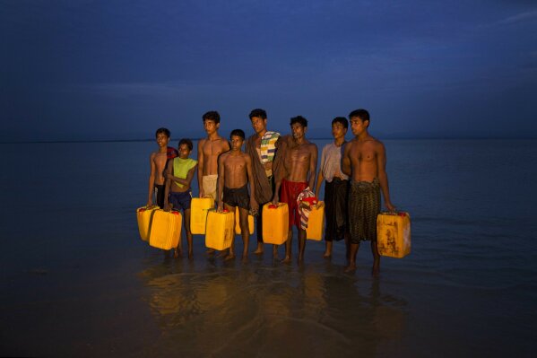 
              In this Nov. 5, 2017, photo, newly arrived Rohingya Muslims carry yellow plastic drums they used as flotation aids and listen to Bangladeshi authorities, not pictured, after swimming across the Naf river at Shah Porir Dwip, Bangladesh. The Naf river is a natural border between Myanmar and Bangladesh. Several young Rohingya Muslims escaping the violence in their homeland of Myanmar are now so desperate that they are swimming to safety into neighboring Bangladesh. (AP Photo/Bernat Armangue)
            
