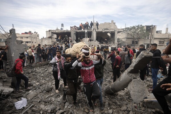 Palestinians evacuate an injured woman after an Israeli airstrike on the Khan Younis refugee camp in the southern Gaza Strip, Thursday, Dec. 7, 2023.  (AP Photo/Mohammed Dahman)