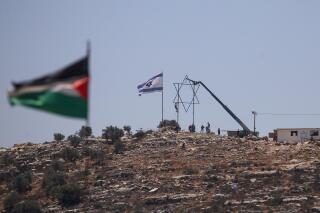 Israeli settlers adjust a large Star of David in the recently established wildcat outpost of Eviatar as it seen from the nearby Palestinian village of Beita, near the West Bank city of Nablus, Friday, July 2, 2021. Israel has reached a compromise with Jewish settlers which they will leave by the end of the week and the area will become a closed military zone, but the houses and roads will remain in place. (AP Photo/Majdi Mohammed)