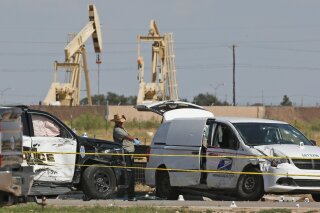 FILE - In this Sunday, Sept. 1, 2019, file photo, law enforcement officials process the crime scene from Saturday's shooting which ended with the shooter, Seth Ator, being shot dead by police in a stolen mail van, right, in Odessa, Texas. Within minutes of media outlets identifying the gunman who killed seven people in West Texas, a Twitter account was spreading false information linking the shooter to Democratic presidential candidate Beto O’Rourke. The speed of the misinformation again illustrates the eagerness of some to baselessly blame mass shootings on particular political ideologies. (AP Photo/Sue Ogrocki, File)