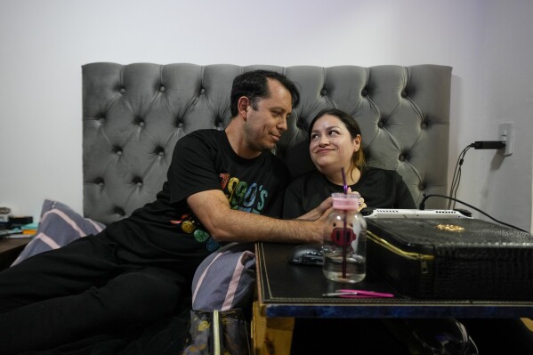 Susana Moreira, 41, a degenerative muscular dystrophy patient, looks at her husband in her bedroom in Santiago, Chile, Thursday, April 10, 2025. (AP Photo/Esteban Felix)