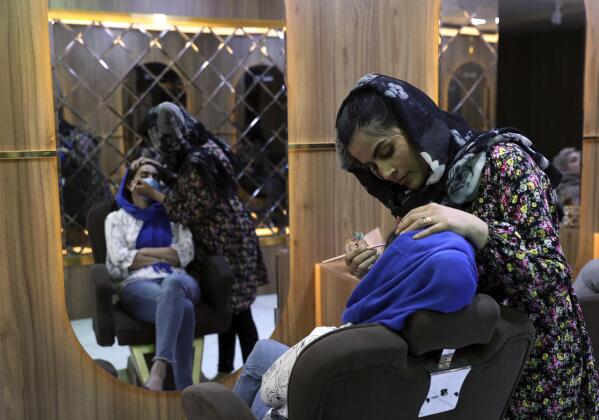 Sultana Karimi applies makeup on a customer at Ms. Sadat’s Beauty Salon in Kabul, Afghanistan, Sunday, April 25, 2021. Kabul's young working women say they fear their dreams may be short-lived if the Taliban return to Kabul, even if peacefully as part of a new government. (AP Photo/Rahmat Gul)