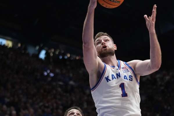 Kansas center Hunter Dickinson (1) beats Texas forward Brock Cunningham to a rebound during the first half of an NCAA college basketball game Saturday, Feb. 24, 2024, in Lawrence, Kan. (AP Photo/Charlie Riedel)