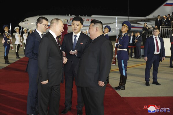 In this photo provided on Wednesday, June 19, 2024, by the North Korean government, Russian President Vladimir Putin, center left, and North Korea's leader Kim Jong Un, center right, talk on the red carpet upon Putin's arrival at the Pyongyang International Airport in Pyongyang, North Korea, early Wednesday, June 19. The content of this image is as provided and cannot be independently verified. Korean language watermark on image as provided by source reads: 