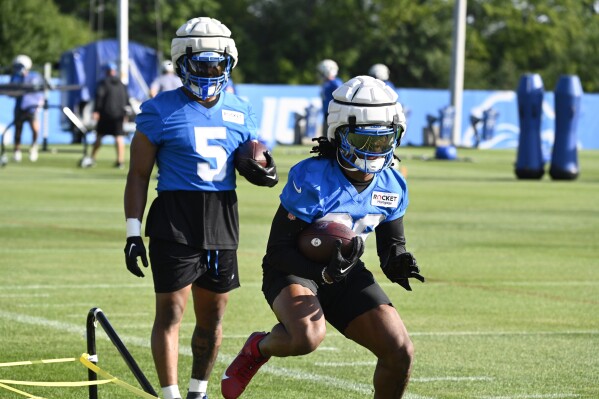 Detroit Lions running back Jahmyr Gibbs, front, runs a drill as David Montgomery looks on during an NFL football practice in Allen Park, Mich., Saturday, July 27, 2024. (AP Photo/Jose Juarez)