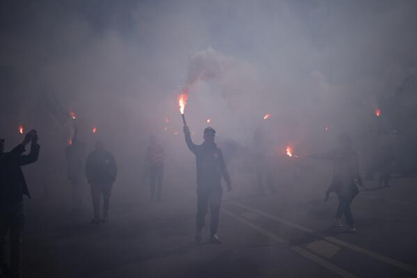 Protesters march with flares during a demonstration in Marseille, southern France, Tuesday, March 28, 2023. France's government is unfurling massively ramped-up security measures for a fresh blast of marches and strikes against unpopular pension reforms. (AP Photo/Daniel Cole)