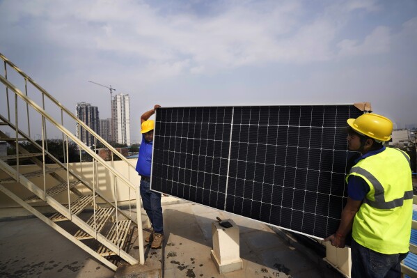 Workers of Solar Square carry a panel on the rooftop of a residence in Gurugram on the outskirts of New Delhi, India, Feb. 20, 2024. (AP Photo/Manish Swarup, File)