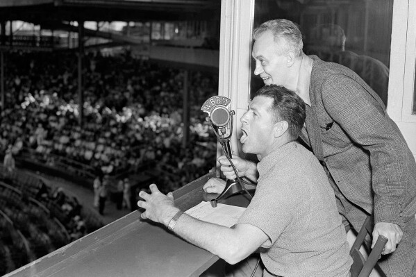FILE - Baseballer Charlie Grimm,left, deposed by the Chicago Cubs in favor of Gabby Hartnett as manager, takes up new duties as a radio broadcaster at the ball games at Wrigley Field in Chicago, July 25, 1938. He's assisted by Pat Flanagan, a broadcasting colleague. Many baseball fans, especially older ones, originally fell in love with America’s pastime by listening to ballgames on AM radio. But several major automakers are eliminating broadcast AM radio from newer models, prompting lawmakers on Capitol Hill to propose legislation that would prevent the practice for safety and other reasons. (AP Photo/File)