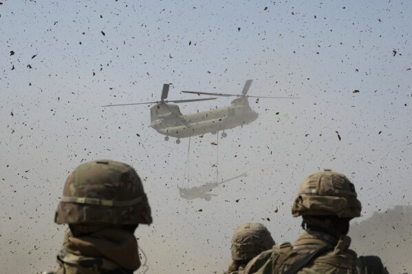 A U.S Army CH-47 Chinook helicopter transports a M777 howitzer during a joint military drill between South Korea and the United States at Rodriguez Live Fire Complex in Pocheon, South Korea, Sunday, March 19, 2023. (AP Photo/Ahn Young-joon)