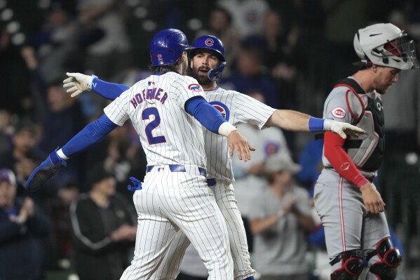 Chicago Cubs' Dansby Swanson, center, celebrates his two-run home run with Nico Hoerner, next to Cincinnati Reds catcher Tyler Stephenson during the eighth inning of a baseball game early Sunday, June 2, 2024, in Chicago. (AP Photo/Charles Rex Arbogast)