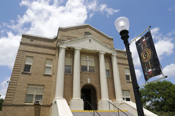 A large cross is mounted over the entrance of the San Jacinto County Courthouse Tuesday, May 16, 2023, in Coldspring, Texas. In 2020, the county settled a whistleblower’s lawsuit accusing Sheriff Greg Capers of wide-ranging misconduct for $240,000. In 2022, county leaders hired a police consulting firm to examine the sheriff’s office but disregarded its recommendation to have the Texas Rangers’ public corruption squad investigate. (AP Photo/Michael Wyke)
