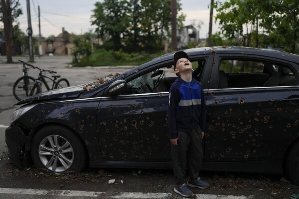 A child looks up at a building destroyed during attacks in Irpin outskirts Kyiv, Ukraine, Monday, May 30, 2022. (AP Photo/Natacha Pisarenko)