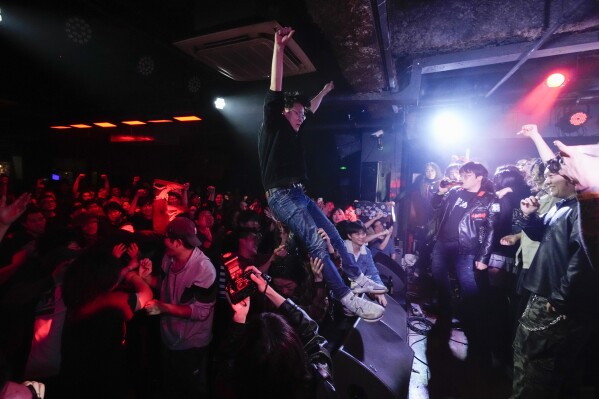 A Chinese punk stage dives to the crowd during a punk festival in Hangzhou, China, Friday, Jan. 17, 2025. (AP Photo/Aaron Favila)