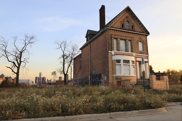 FILE - A graffiti-marked abandoned home north of downtown Detroit, in background, is seen, Oct. 24, 2013. Detroit entered 2014 in bankruptcy, facing $18 billion or more in debt. A decade later, the Motor City has risen from the ashes of insolvency, with balanced budgets, revenue increases and millions of dollars socked away. (AP Photo/Carlos Osorio, File)