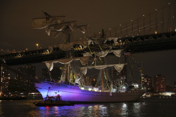 A New York Police Department harbor unit passes in front of the Cuauhtémoc, a masted Mexican Navy training ship as it sits stranded near the Manhattan Bridge after colliding with the Brooklyn Bridge, Saturday, May 17, 2025, in New York. (AP Photo/Yuki Iwamura)