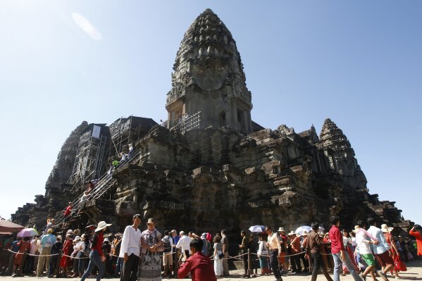 FILE - In this Sunday, Dec. 31, 2017, file photo, tourists line up for stepping up Angkor Wat temple outside Siem Reap, Cambodia. Cambodia is closing the Angkor temple complex to visitors because of a growing COVID-19 outbreak. The temples at Angkor, built between the 9th and 15th centuries, are Cambodia’s biggest tourist attraction, though the pandemic has reduced the number of visitors dramatically. The Apsara Authority that oversees the site says the ban on visitors will last until April 20. (AP Photo/Heng Sinith, File)