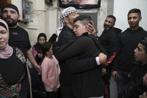 Ahmed Salaima, 14, center, a Palestinian prisoner released by Israel, is hugged by his father as he arrives home in the east Jerusalem neighborhood of Ras al-Amud Tuesday, Nov. 28, 2023. (AP Photo/Mahmoud Illean)
