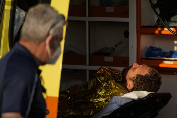 FILE - Paramedics carry an injured survivor of a shipwreck to an ambulance at the port in Kalamata town, about 240 kilometers (150miles) southwest of Athens, Greece on June 14, 2023. The international rights groups Amnesty International and Human Rights Watch allege on Thursday, Dec. 14, 2023, that Greek authorities have failed to properly investigate allegations by some survivors that the rescue mission had been mishandled. (AP Photos/Thanassis Stavrakis, File)