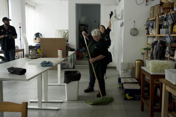 Christian volunteers Elisabeth Odegaard, rear right, Claudio Rafael, left, and Jannie Slim, center, clean up after preparing food for Israeli soldiers on a brief respite from combat operations in the Gaza Strip, in Tel Aviv, Wednesday, March 6, 2024. Her visit to Israel is part of a wave of religious "voluntourism" to Israel, organized trips that include some kind of volunteering aspect connected to the ongoing war in Gaza. Israel's Tourism Ministry estimates around a third to half of the approximately 3,000 visitors expected to arrive each day in March are part of faith-based volunteer trips. Prior to Oct. 7, around 15,000 visitors were arriving in Israel per day, according to Tourism Ministry statistics. (AP Photo/Maya Alleruzzo)