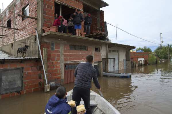 Rescue workers bring food to a family whose home was flooded following heavy rains in Campana, Argentina, Saturday, May 17, 2025. (AP Photo/Rodrigo Abd)