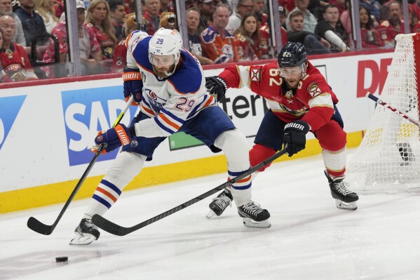 Edmonton Oilers center Leon Draisaitl (29) and Florida Panthers defenseman Brandon Montour (62) go after the puck during the third period of Game 2 of the NHL hockey Stanley Cup Finals, Monday, June 10, 2024, in Sunrise, Fla. (AP Photo/Wilfredo Lee)