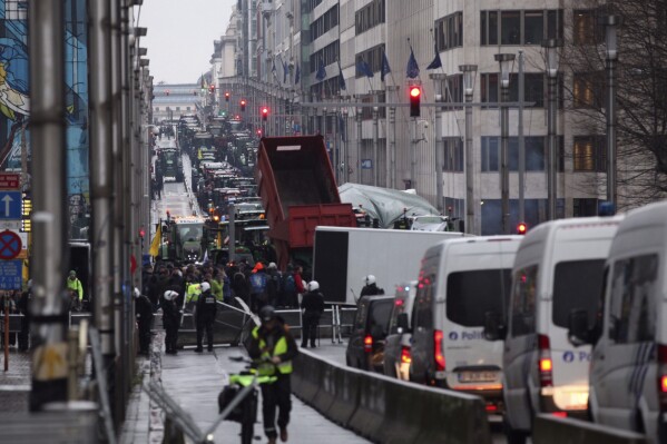 Tractors and police vans face each other at a blockade in the European Quarter during a protest of farmers outside a meeting of EU agriculture ministers in Brussels, Monday, Feb. 26, 2024. European Union agriculture ministers meet in Brussels Monday to discuss rapid and structural responses to the crisis situation facing the agricultural sector. (AP Photo/Nicolas Landemard)