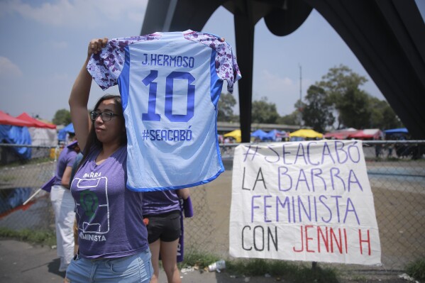 A woman holds up a soccer jersey that reads in Spanish 