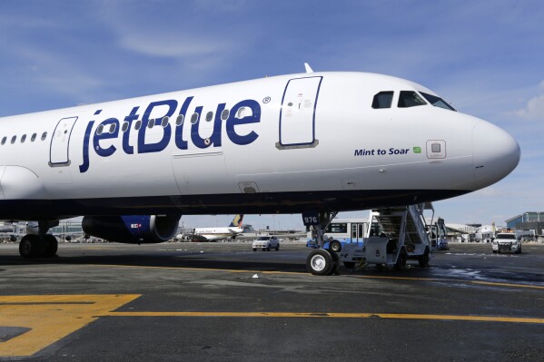 FILE - A JetBlue airplane is shown at John F. Kennedy International Airport in New York, March 16, 2017. JetBlue said Tuesday, Aug. 1, 2023, that its shares are losing altitude and warns that third-quarter and full-year results will be worse than it had previously expected. (AP Photo/Seth Wenig, File)