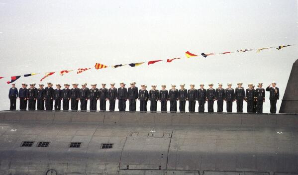 FILE - Crew members of the nuclear submarine Kursk, one of Russia's largest and most advanced submarines, stand on the ship deck during the naval parade in Severomorsk, Russia, July 30, 2000. Kursk Captain Gennady Lyachin stands at right. Retired Vyacheslav Popov has alleged in an interview released Monday Nov. 22, 2021, that the 2000 Kursk submarine disaster was caused by a collision with a NATO sub, an unproven claim that defies the official conclusion that the country's worst post-Soviet naval catastrophe was triggered by a faulty torpedo. (AP Photo/File)