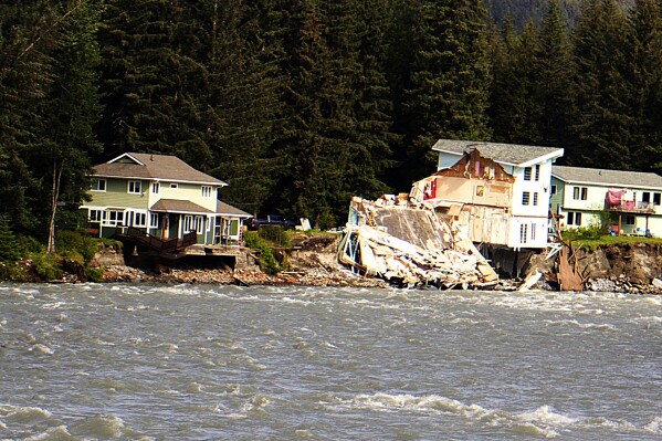 A home hangs over the edge of an eroded riverbank after part of the neighboring house fell into the Mendenhall River in Juneau, Alaska, on Sunday, Aug. 6, 2023. The city of Juneau says the Mendenhall River flooded on Saturday because of a major release from Suicide Basin above Alaska's capital city, and at least two buildings were destroyed. (Mark Sabbatini/Juneau Empire via AP)