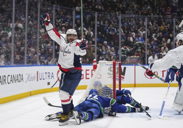 Washington Capitals' Alex Ovechkin, left, celebrates his goal as Vancouver Canucks' Pius Suter, bottom center, and Filip Hronek, back, lie on the ice during the second period of an NHL hockey game in Vancouver, British Columbia, Saturday, March 16, 2024. (Darryl Dyck/The Canadian Press via AP)
