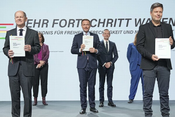 FILE - Front from left, Olaf Scholz, then Chancellor-designate, FDP leader Christian Lindner and Robert Habeck of the Green Party, hold the coalition agreement at the signing of the coalition agreement between the SPD, the Greens and the FDP to form a federal government in Berlin, Tuesday, Dec. 7, 2021. Members of the Free Democrats (FDP), the smallest party in German Chancellor Olaf Scholz’s unpopular coalition, have voted in a low-profile ballot to stay in the troubled government, but the result underlines the three-party alliance’s difficulties. (Michael Kappeler/dpa via AP, File)